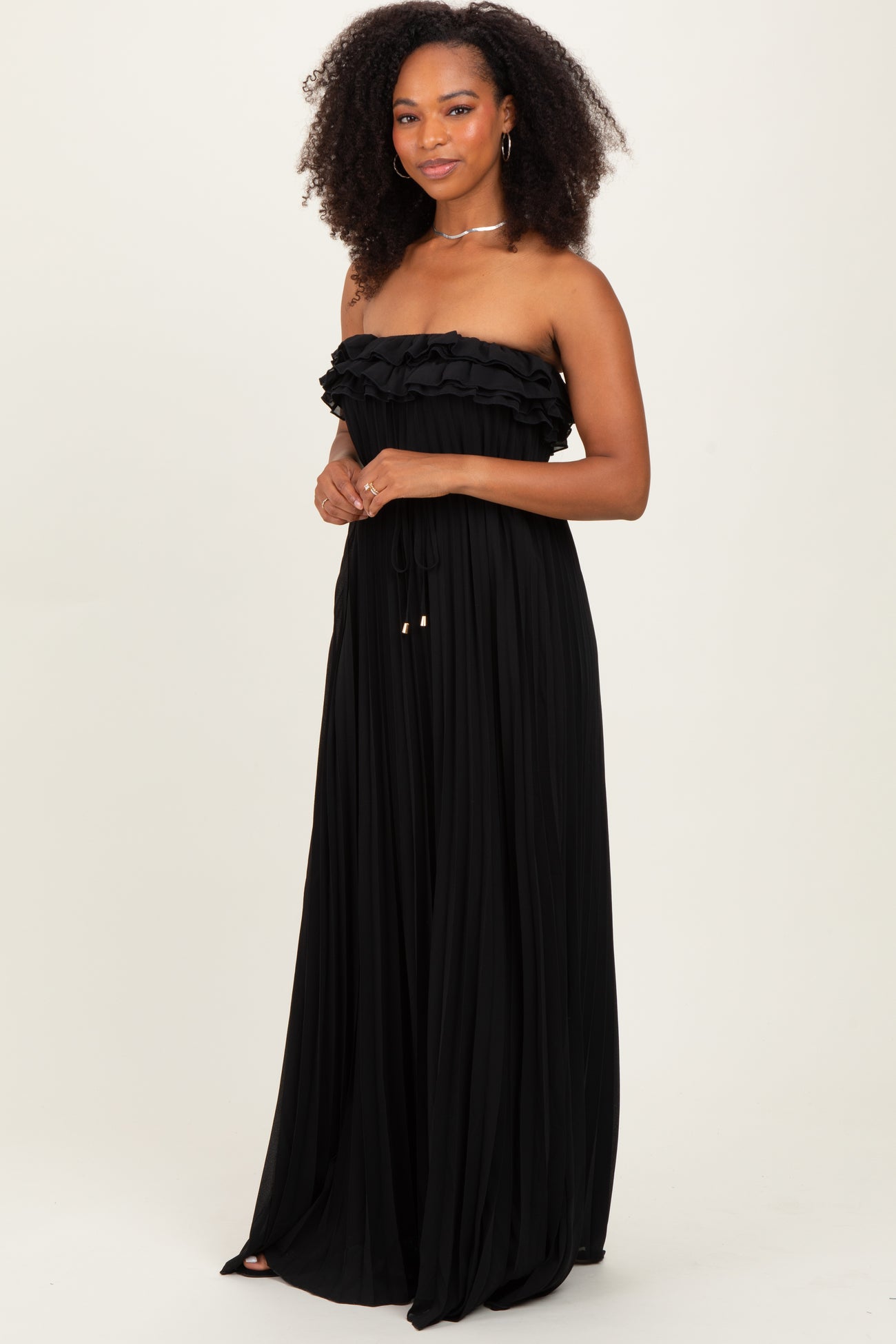 woman wearing a black strapless maxi dress with ruffle details and drawstring accents
