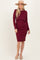 woman wearing a burgundy ribbed long sleeve dress with a ruffled waist and a wide-brimmed hat
