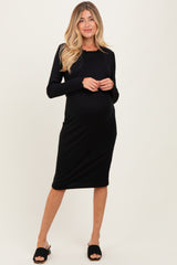woman wearing a black ribbed maternity dress with long sleeves and a visible baby bump