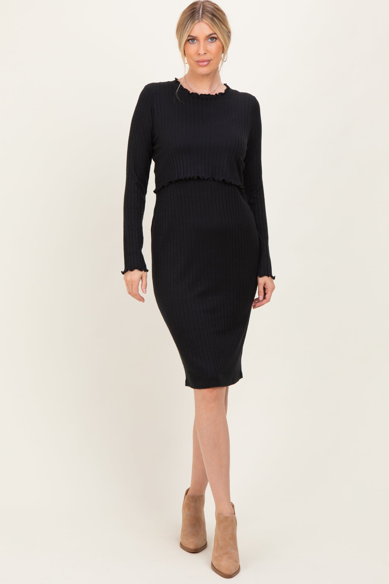 woman wearing a black ribbed long sleeve dress with a fitted silhouette and ruffled hem details