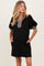 woman wearing a black maternity dress with puff sleeves and a checkered neckline, featuring pockets