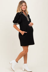 woman wearing a black maternity dress with a checkered collar and puffed sleeves, holding her baby bump