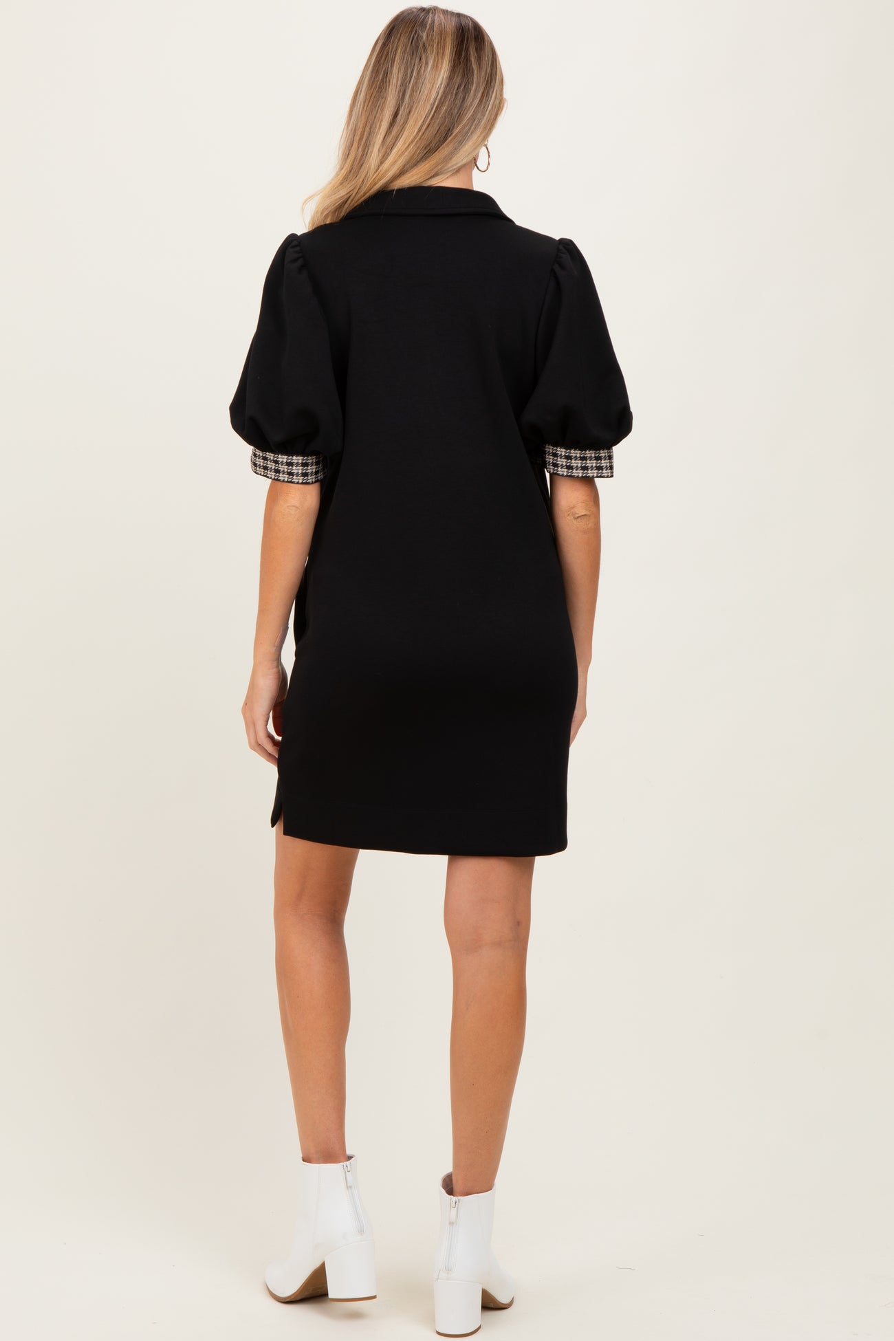 woman wearing a black maternity dress with puff sleeves and plaid detail on the sleeves, viewed from the back