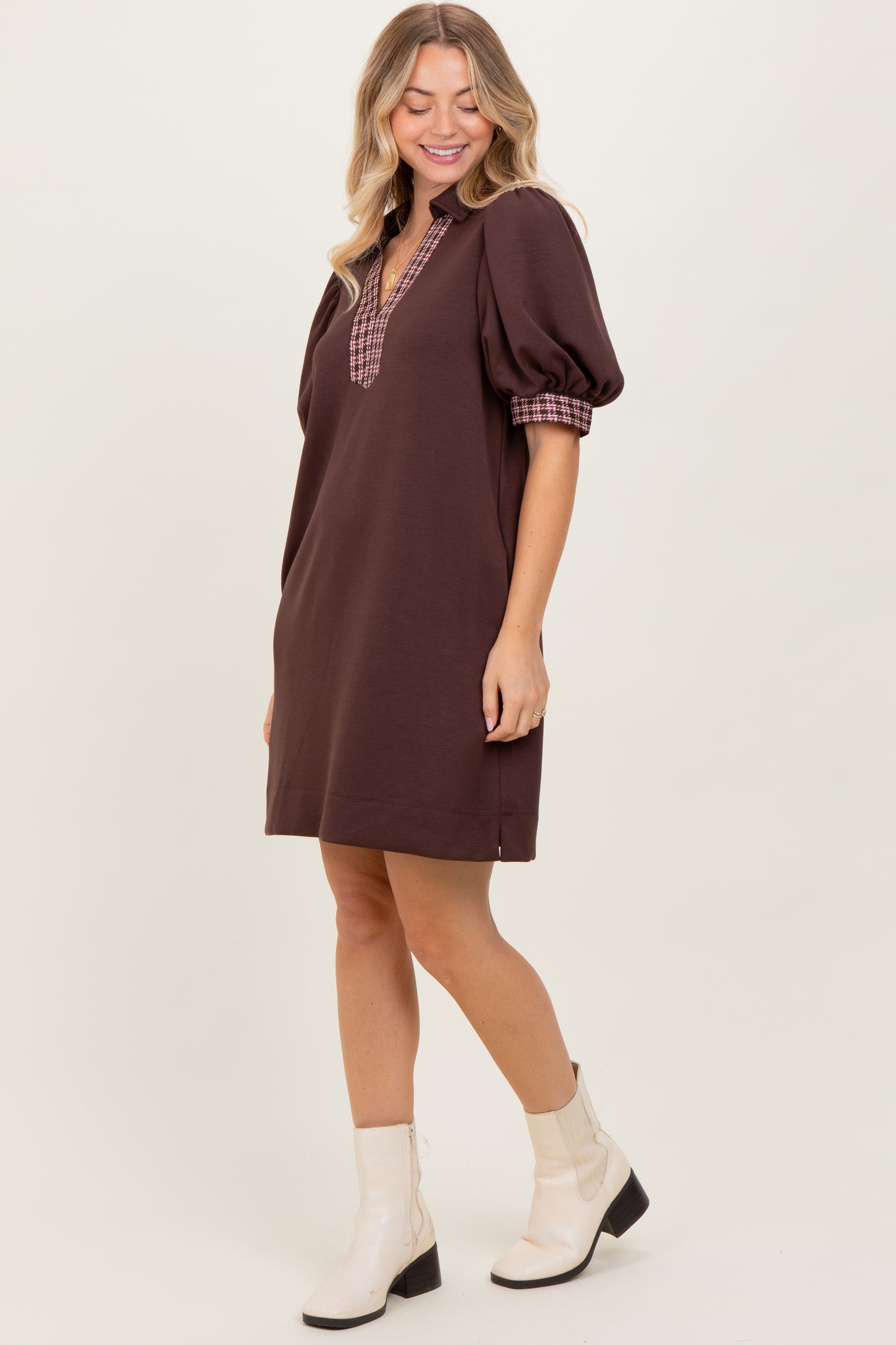 woman wearing a brown puff sleeve mini dress with a checkered collar and white ankle boots