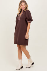 woman wearing a brown puff sleeve mini dress with a checkered collar and white ankle boots