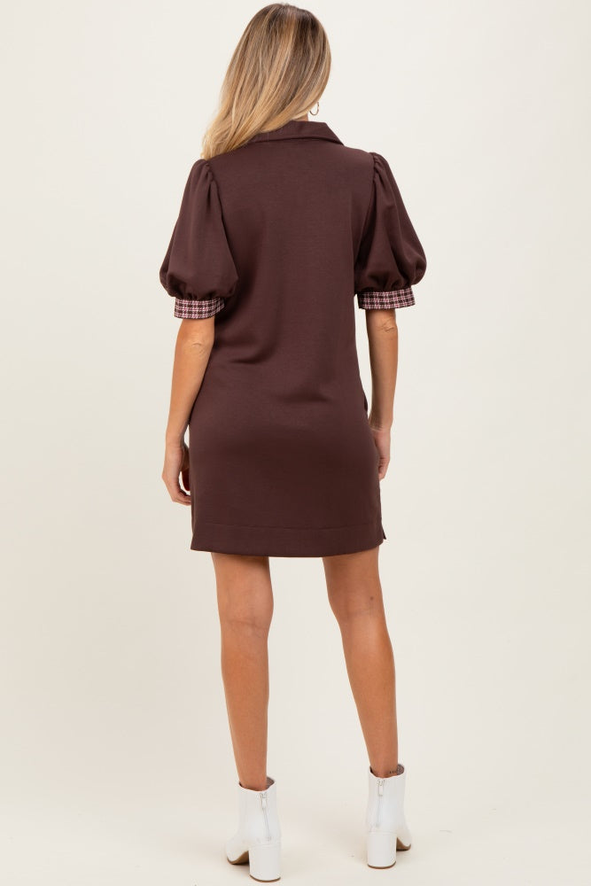 woman wearing a brown maternity dress with puff sleeves and a plaid detail on the sleeves, showing the back view