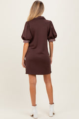 woman wearing a brown maternity dress with puff sleeves and a plaid detail on the sleeves, showing the back view