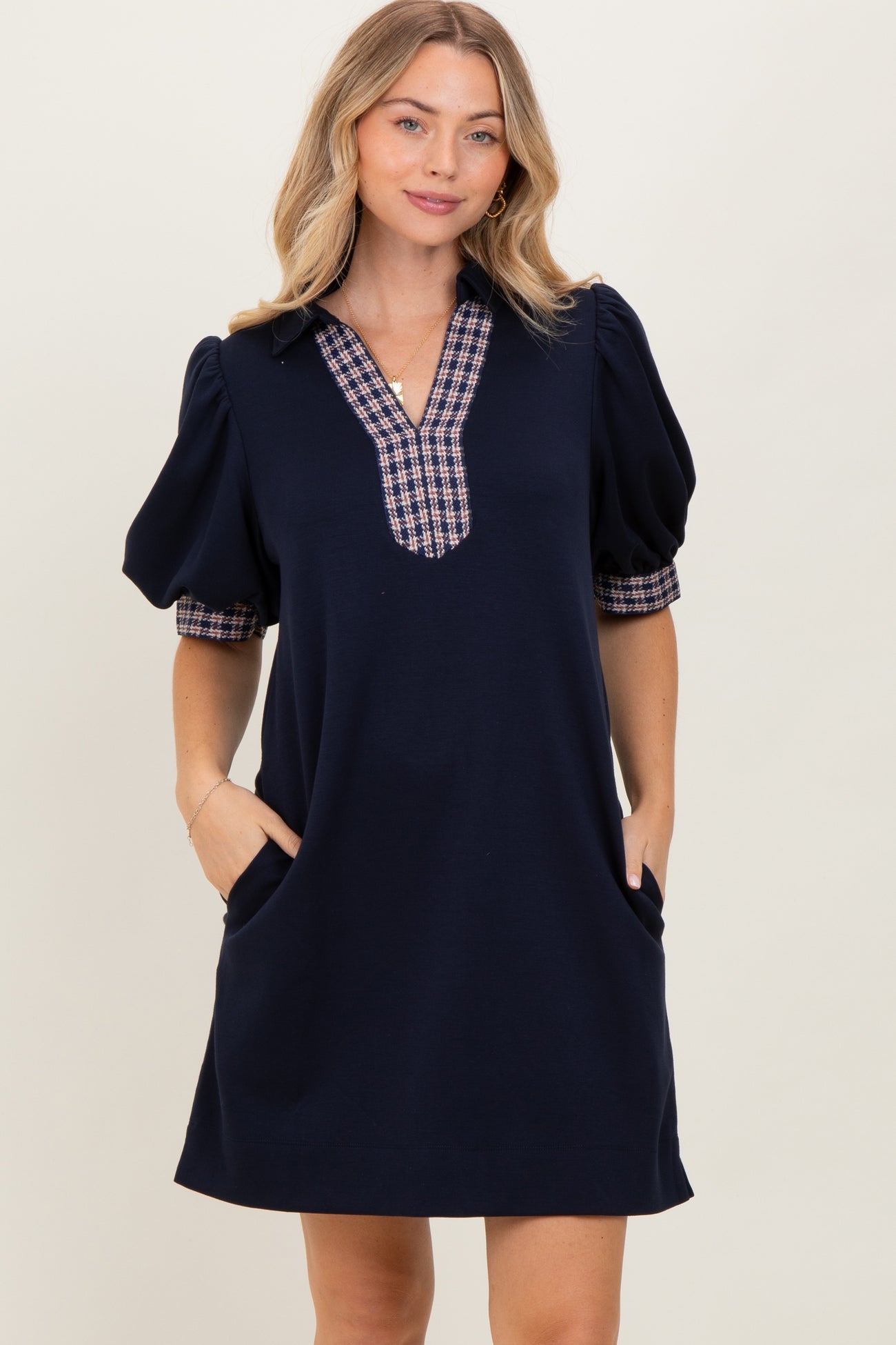 woman wearing a navy short sleeve dress with plaid detail on the sleeves and pockets