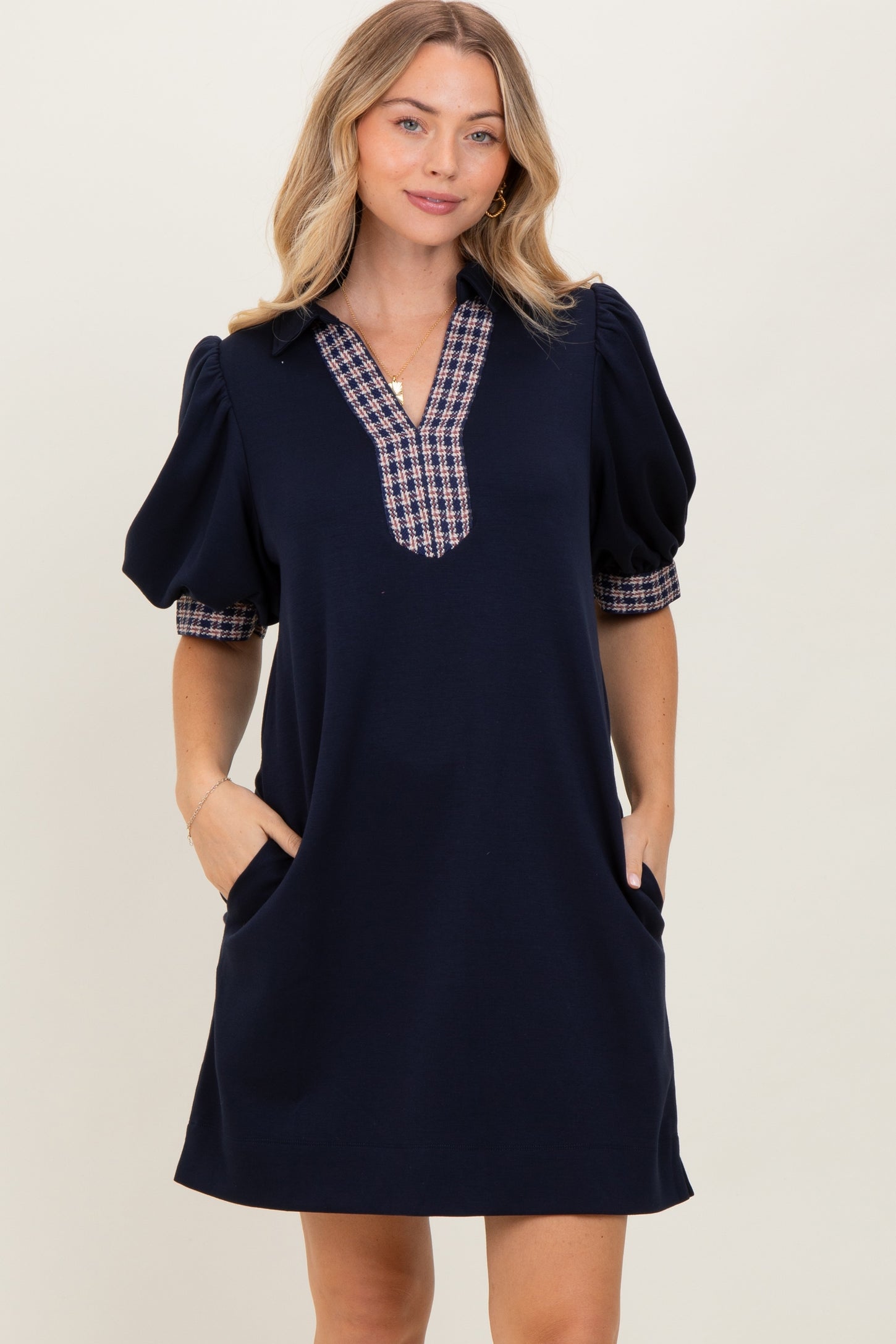 woman wearing a navy short sleeve dress with plaid detail on the sleeves and pockets