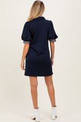 woman wearing a navy blue maternity dress with puff sleeves and plaid cuffs, showcasing a stylish back view