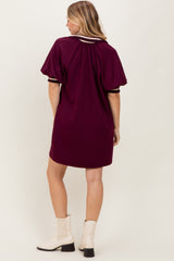woman wearing a maroon short sleeve dress with a relaxed fit and striped detailing on the sleeves, seen from the back