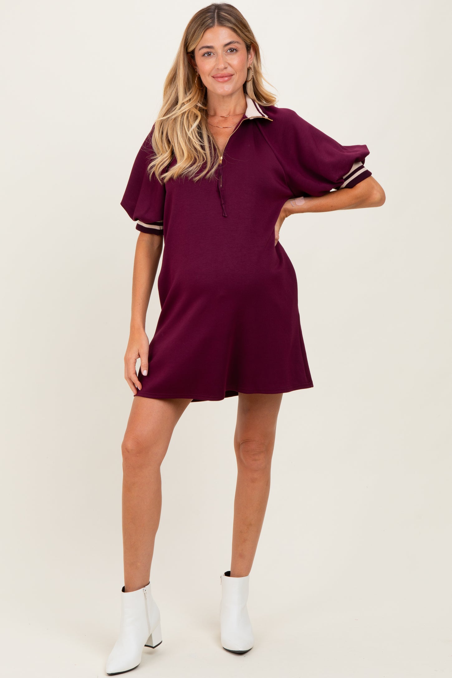 woman wearing a burgundy maternity polo dress with short sleeves and striped details, showing a baby bump