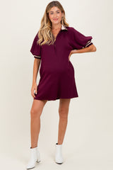 woman wearing a burgundy maternity polo dress with short sleeves and striped details, showing a baby bump