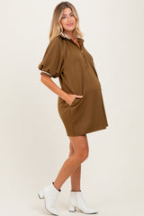 woman wearing a brown maternity dress with a collar, short sleeves, and pockets, showing her baby bump