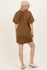 woman wearing a brown short sleeve dress with a relaxed fit, styled with a beige cap and white sandals