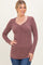 woman wearing a burgundy long sleeve ribbed top with a v-neck and gathered detail at the front