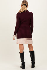 woman wearing a maroon ribbed maternity dress with a pink striped hem and long sleeves, showing off the baby bump