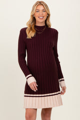 woman wearing a maroon and cream maternity sweater dress with a ribbed texture and long sleeves, showing her baby bump