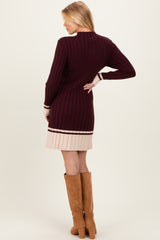 woman wearing a burgundy ribbed maternity sweater dress with pleated pink hem and tall brown boots, showing style from the back