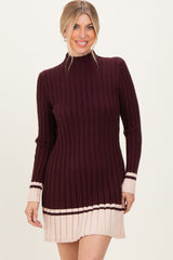 woman wearing a burgundy ribbed knit sweater dress with cream stripes at the hem and cuffs