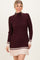 woman wearing a burgundy ribbed knit sweater dress with cream stripes at the hem and cuffs