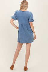 woman wearing a light blue denim puff sleeve dress, showing the back view with a slightly flared skirt