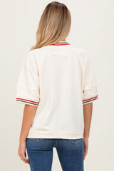 woman wearing a cream maternity sweatshirt with red and green striped details on sleeves and casual fit, showing back view