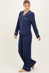 woman wearing a navy blue long sleeve pajama set with white piping details, featuring a button-up shirt and relaxed fit pants
