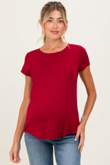 woman wearing a dark red short sleeve maternity top and showing her baby bump