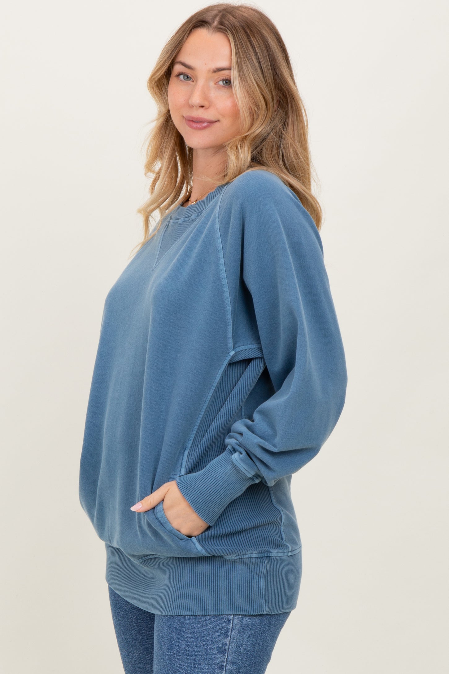 woman wearing a blue oversized sweatshirt with a relaxed fit and side pockets
