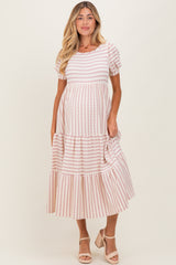 woman wearing a pink and white striped maternity dress with short sleeves and a tiered skirt, holding her baby bump