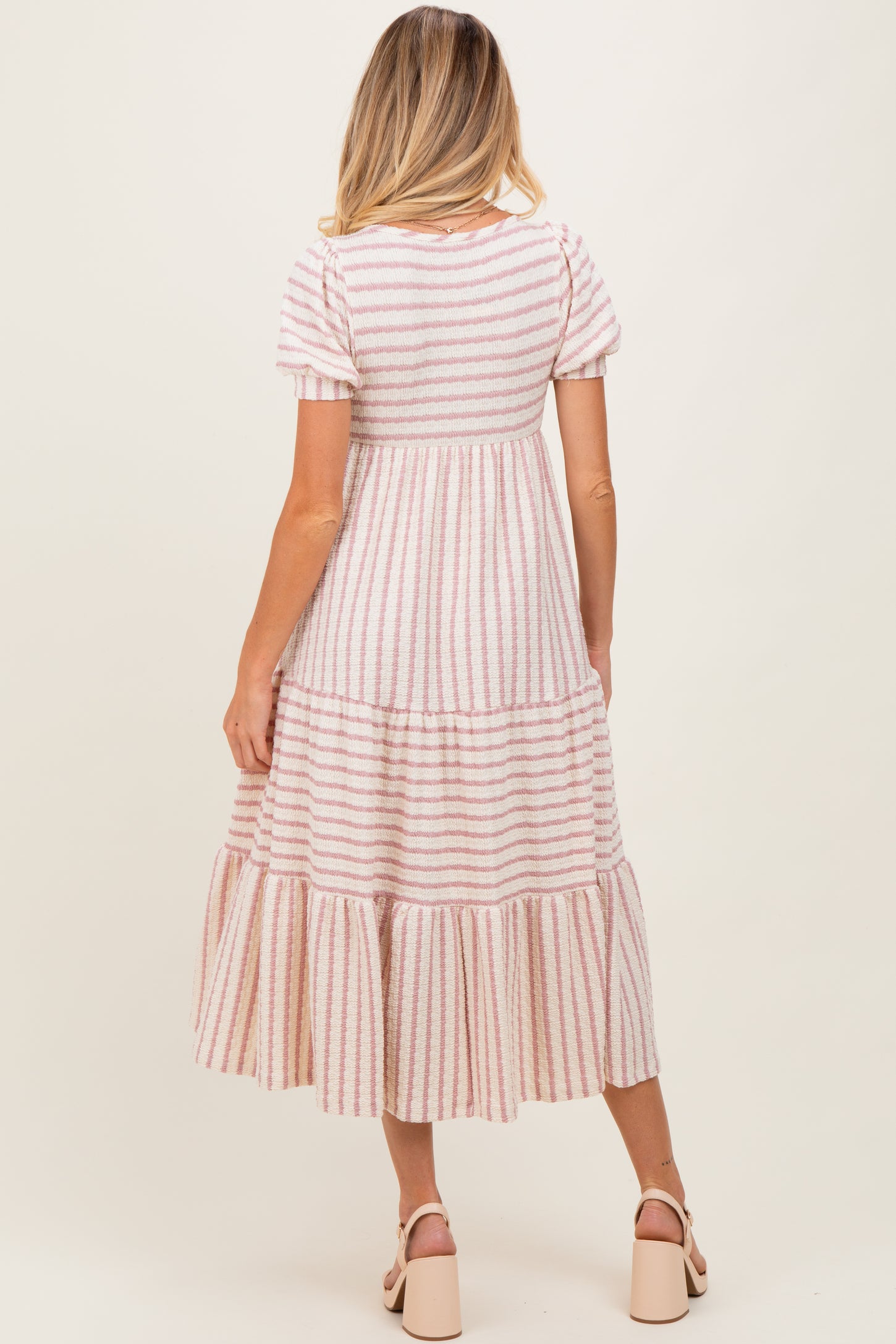 woman wearing a striped maternity maxi dress with tiered ruffles and short sleeves, showing her baby bump from the back