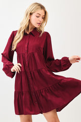 woman wearing a burgundy long sleeve tiered shirt dress with a button-down front and puff sleeves