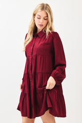 woman wearing a burgundy long sleeve button-up tiered dress with a relaxed fit and cuffed sleeves