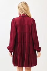 woman wearing a burgundy long sleeve tiered mini dress with a collar and puff sleeves