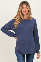 woman wearing a dark blue ribbed maternity sweater with a visible baby bump and long sleeves