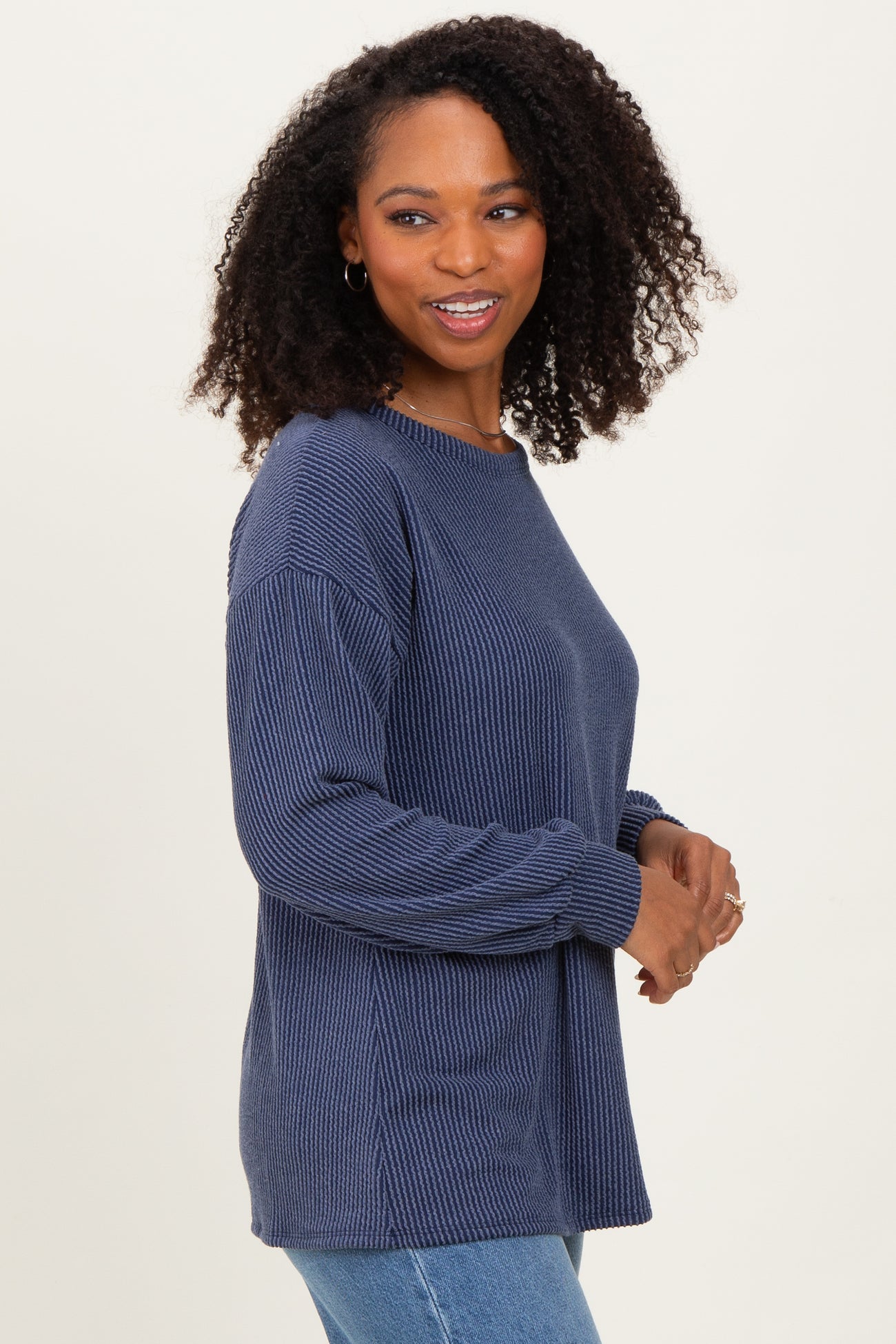 woman wearing a dark blue ribbed knit sweater with long sleeves and relaxed fit, smiling at the camera