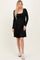 woman wearing a black long sleeve wrap dress with a tie detail at the waist and white sneakers