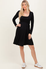 woman wearing a black long sleeve wrap dress with a tie waist and white sneakers