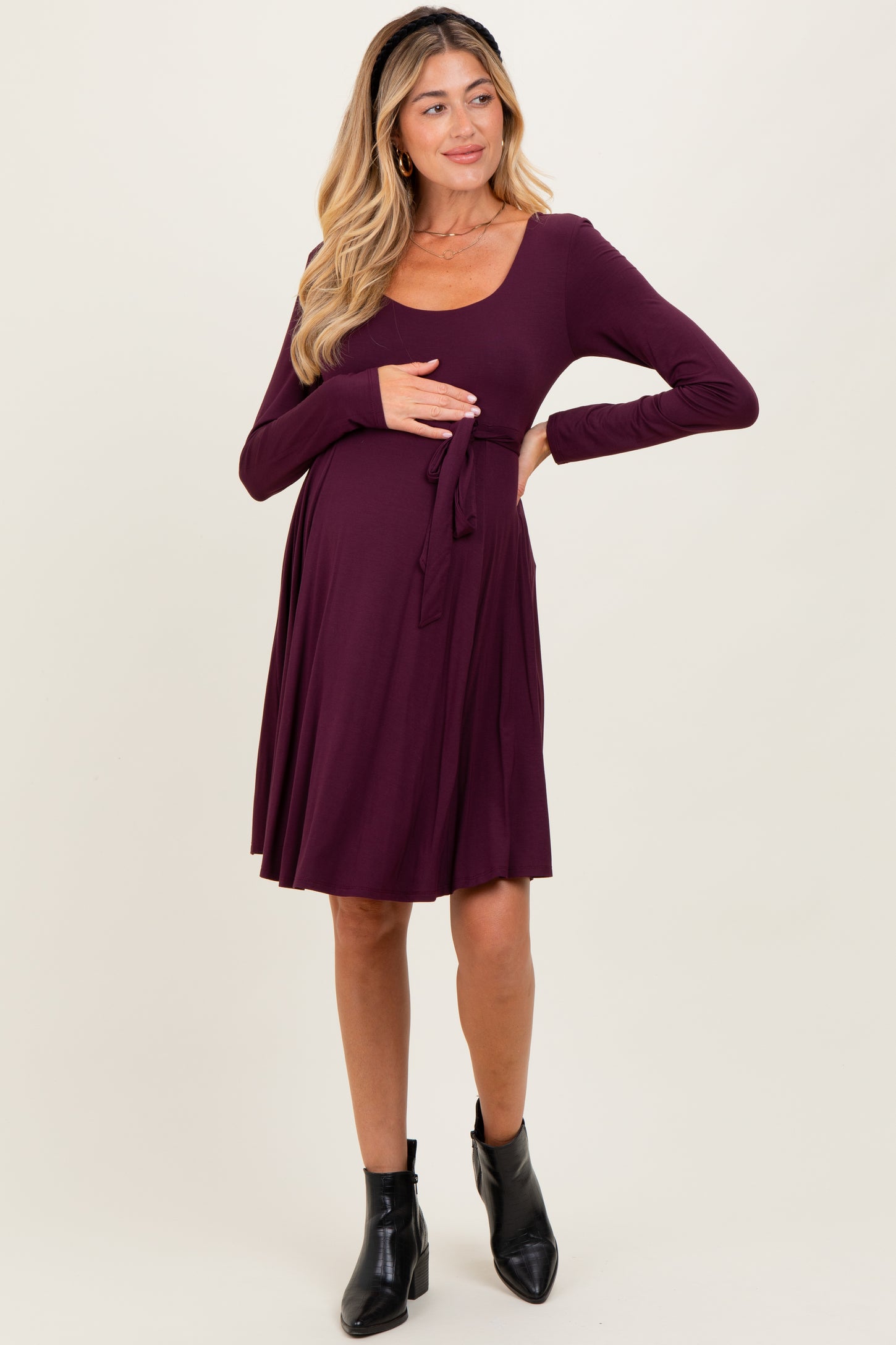 woman wearing a plum long sleeve maternity dress with a tie waist, showing her baby bump