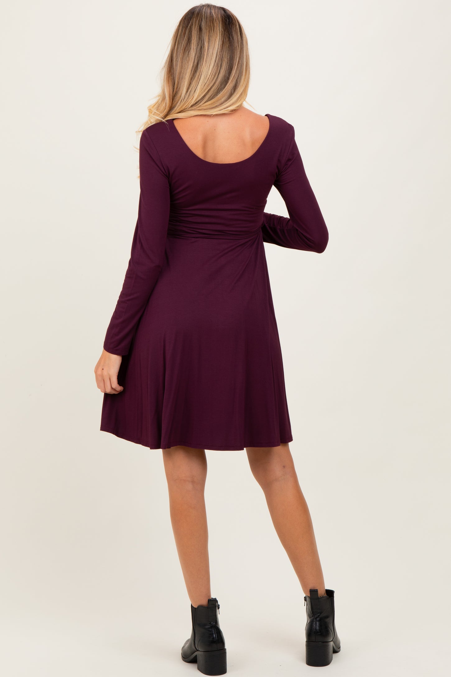 woman wearing a burgundy long sleeve maternity dress with an A-line cut and a scoop back view