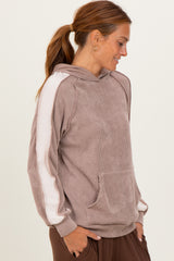 woman wearing a brown striped hoodie with white side stripes and a front pocket, smiling and looking to the side