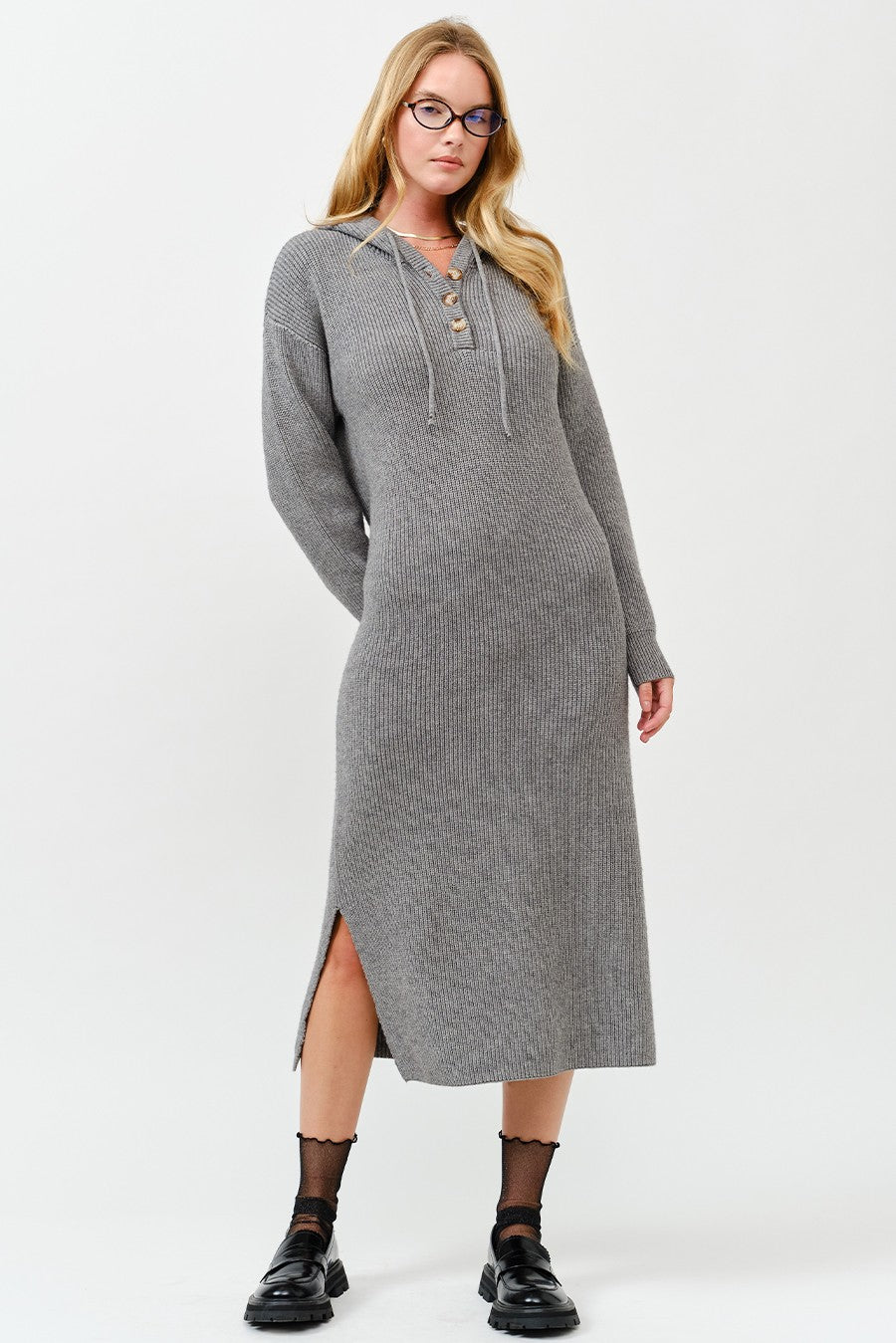 woman wearing a gray ribbed long sleeve midi dress with side slits and a lace-up neckline