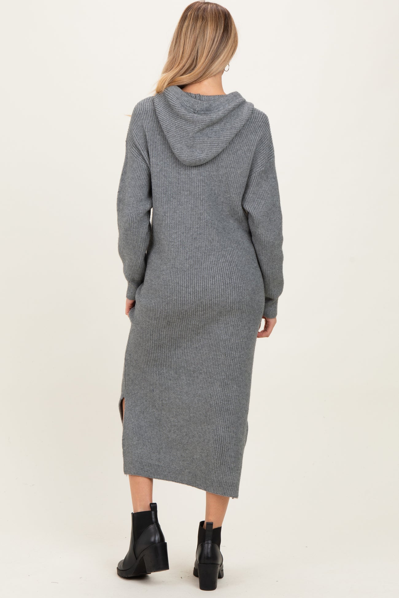 woman wearing a gray knitted maternity sweater dress with a hood and side slits, showing her baby bump from the back
