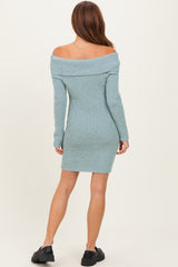 woman wearing a ribbed off-the-shoulder teal sweater dress, view from the back, paired with black slip-on shoes