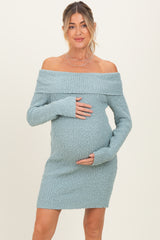 woman wearing a light blue off-the-shoulder maternity dress and holding her baby bump