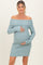 woman wearing a light blue off-the-shoulder maternity dress and holding her baby bump