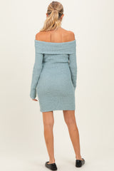 woman wearing a light blue off-the-shoulder knit maternity dress, showing a fitted silhouette from the back