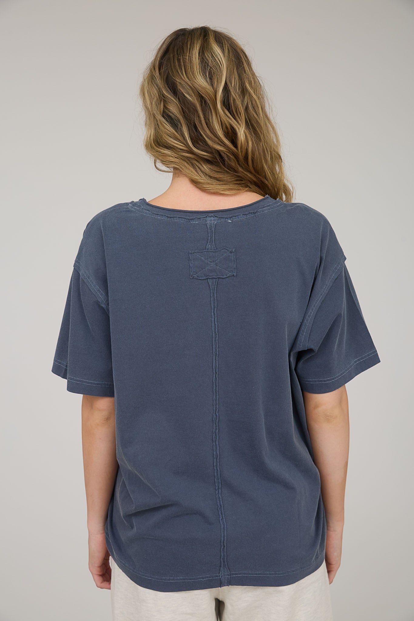 woman wearing a washed navy blue oversized t-shirt with a relaxed fit and short sleeves viewed from the back