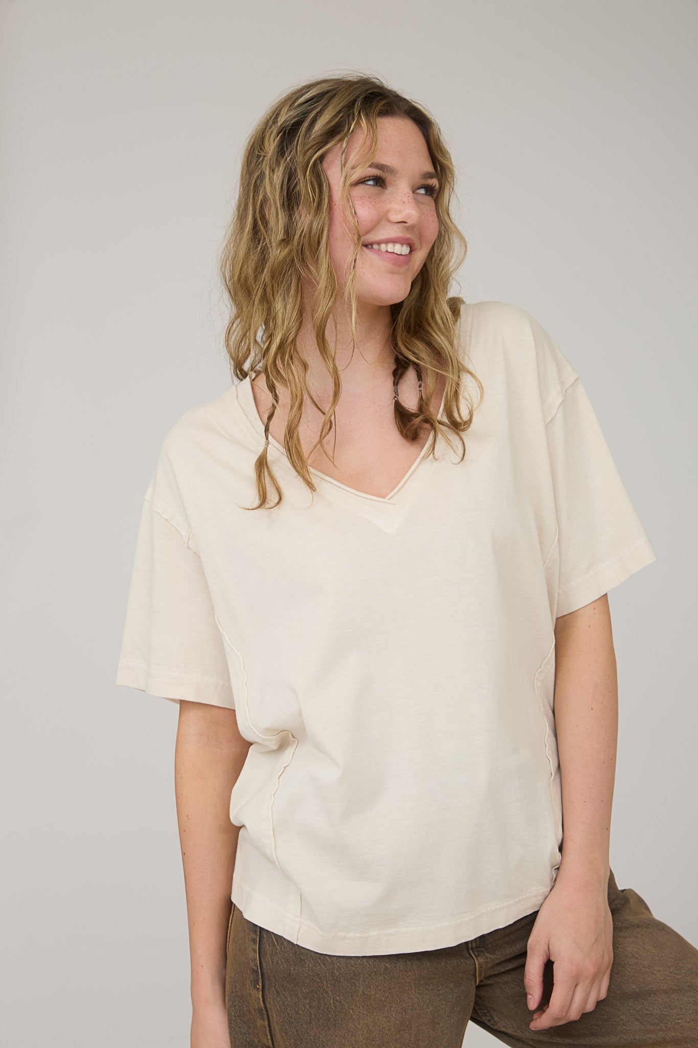 woman wearing a beige v-neck oversized t-shirt with short sleeves and a relaxed fit